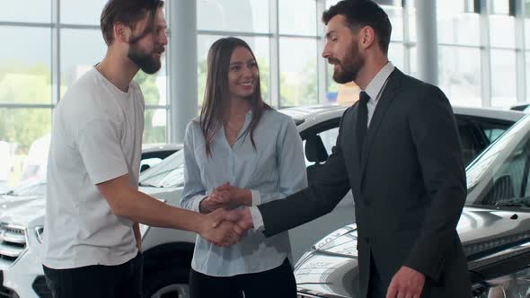 Professional Car Salesman Is Telling Interested Buyers Beautiful Couple About Luxurious Car in Motor