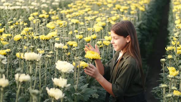 Little Girl Smells Yellow Flowers at a Plant