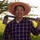 Slow motion Happy Asian Farmer holding a hoe and looking at camera green paddy field on background. - VideoHive Item for Sale