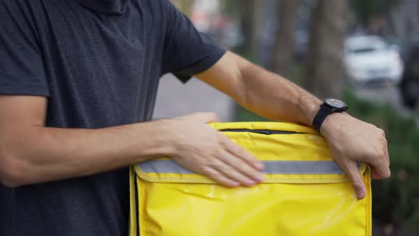 Cheerful Courier Zipping Yellow Backpack Ready to Deliver Order