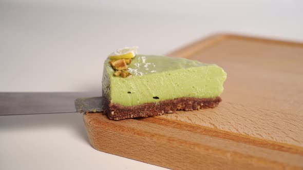 A slice of homemade organic avocado cake is placed on a wooden chopping board. 