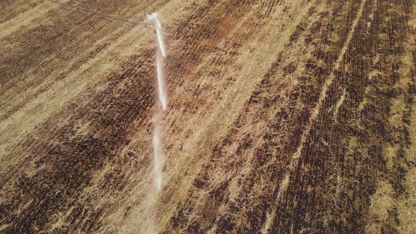 Agriculture field with Irrigation system rain guns sprinkler on after harvest