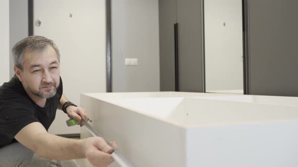 A Furniture Maker Measures Parts with a Tape Measure When Assembling Furniture