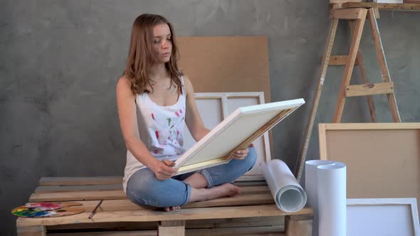 A Woman Artist Sits in an Art Studio and Looks at a Painting