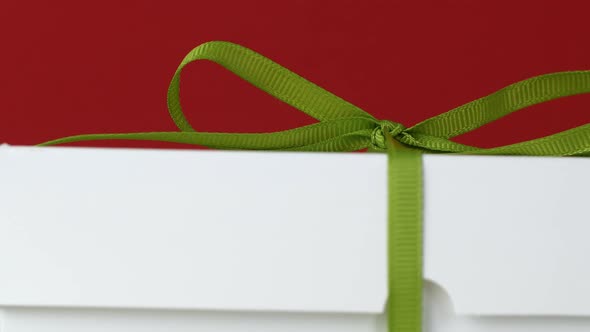 Gift box with bow isolated on red Christmas background. Gifts for the holiday close-up of packaging.