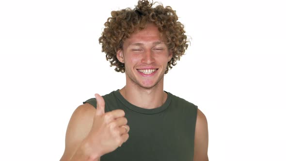 Caucasian Curly Cheerful Guy with Green Eyes Looking on Camera Smiling Showing Thumb Up Over White