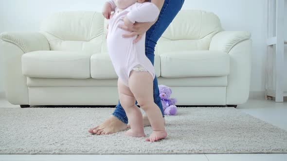 Baby Taking First Steps with Mother's Help at Home