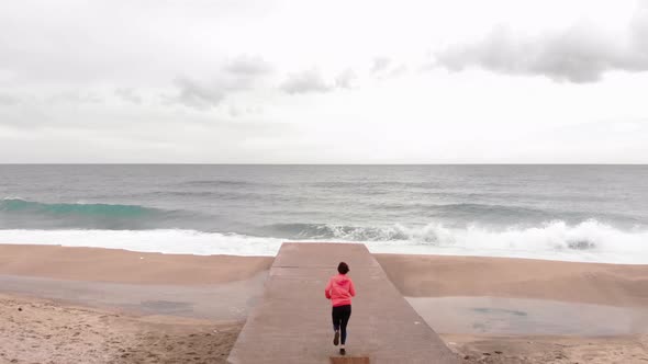 Sporty female runs to edge of sea pier and admires stunning beautiful landscape