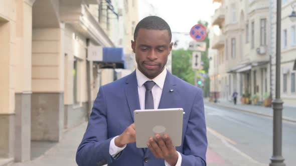 African Businessman Making Video Call on Tablet While Walking on Street