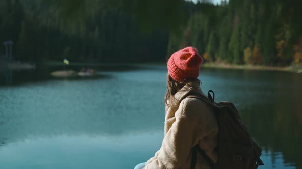 Portrait of Inspired Beautiful Smiling Woman Hiker Backpacker Sitting on Wooden Pier at Beautiful