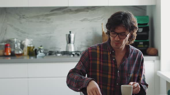 Concentrated adult man in a plaid shirt having breakfast