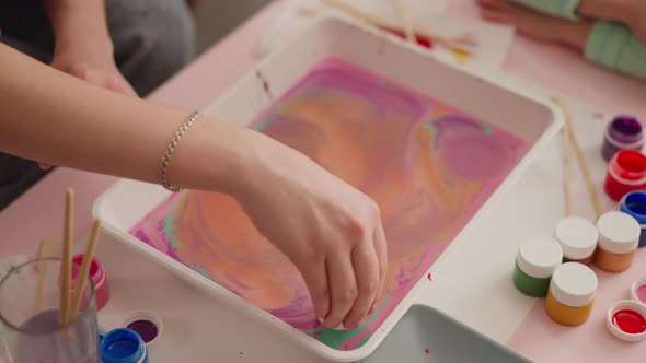 Young Woman Puts Egg Into Tray with Mix for Marbling Design