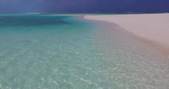 Beautiful fly over abstract shot of a sandy white paradise beach and blue ocean background in colour