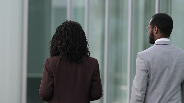 Back View of Two People Wearing Suits Walking Near Office Building