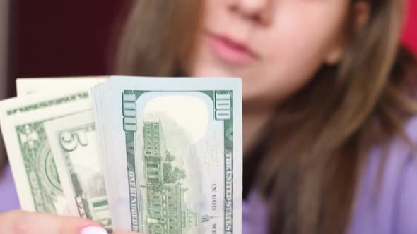 Caucasian young brunette woman 20 years old counting cash 100 dollar bills holding in her hands. Pos