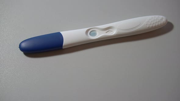 Pregnancy Test is Lying on a White Background and Revealing Positive Result in Macro