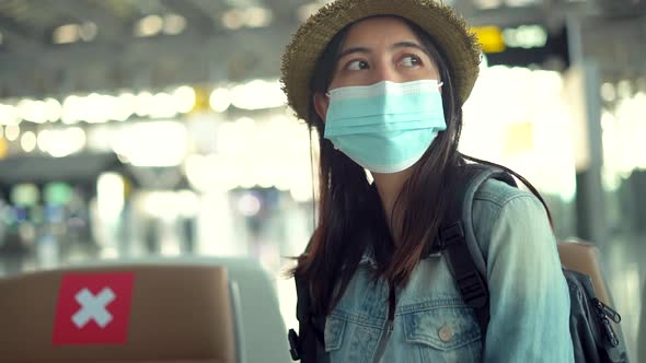 Asian woman traveler wear protective mask sitting with distance at the airport.
