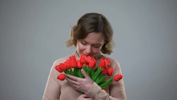 Pretty Lady Holding Flowers Smiling on Grey Background, Holiday Gift, Femininity