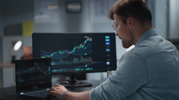 Side View of Financial Expert Analyze Graphs on Computer and Drink Coffee Working Late in Office