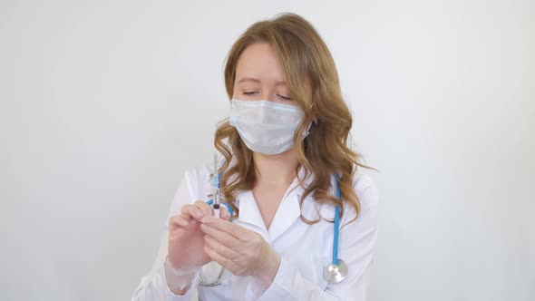 A doctor around his neck holds a medical syringe in his hands before an injection