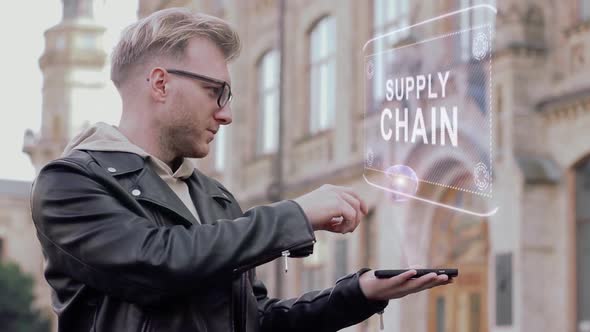 Smart Young Man with Glasses Shows a Conceptual Hologram Supply Chain