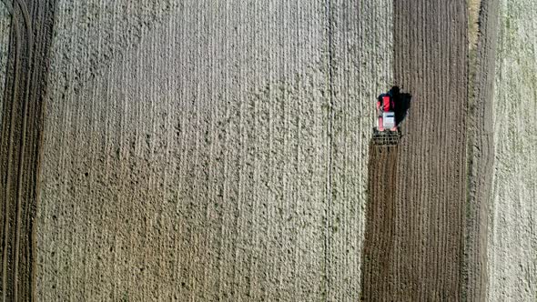Red tractor plowing a spring field, aerial view, Poland