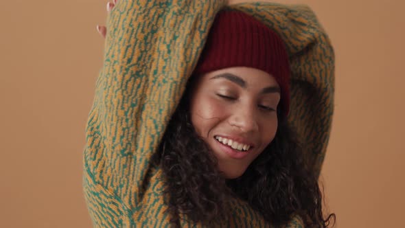 Positive African curly-haired woman posing with raising arms