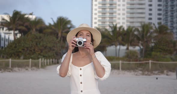 Smiling woman with a retro camera on the beach. Shot on Black Magic Cinema Camera