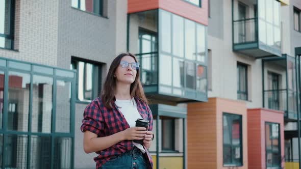 Young Attractive European Girl with Coffee While Walking Looks Around