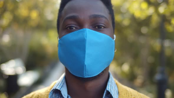 Portrait of Young African Man with Medical Protective Mask on Face Outdoors