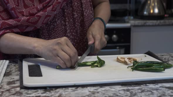Hands Of Ethnic Minority Female Chopping Fresh Green Chillies On A Board. Locked Off