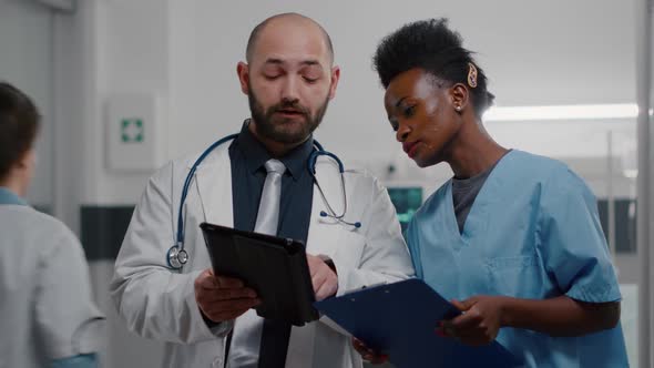 Practitioner Doctor with Afro American Assistant Analyzing Recovery Treatment