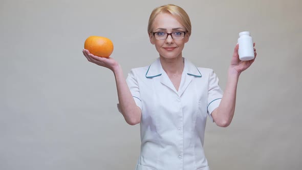 Nutritionist Doctor Healthy Lifestyle Concept - Holding Organic Grapefruit and Jar of Vitamin Pills