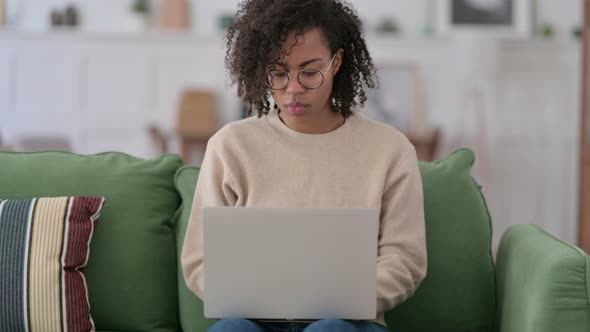 Young African Woman with Laptop Reacting To Failure on Sofa 