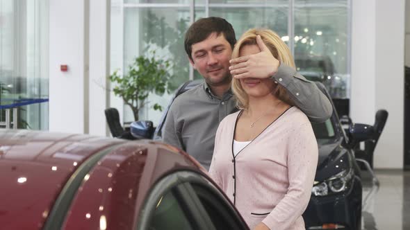 Loving Husband Presenting His Wife a New Car at the Dealership