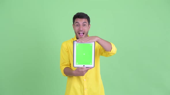 Happy Young Hispanic Businessman Showing Digital Tablet and Looking Surprised