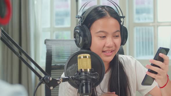 Over Shoulder View, Asian Kid Girl Holding Phone Singing While Recording Podcast