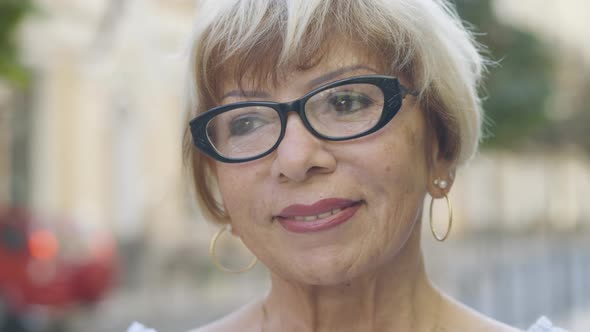 Close-up Face of Charming Senior Caucasian Woman in Eyeglasses in Sunlight Outdoors. Portrait of