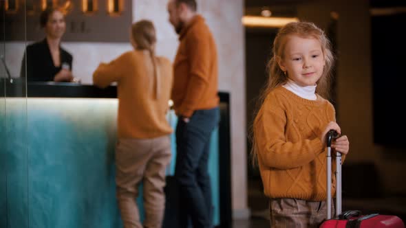 A Family Checking in the Luxury Hotel - a Little Girl Standing with a Suitcase and Waiting for Her