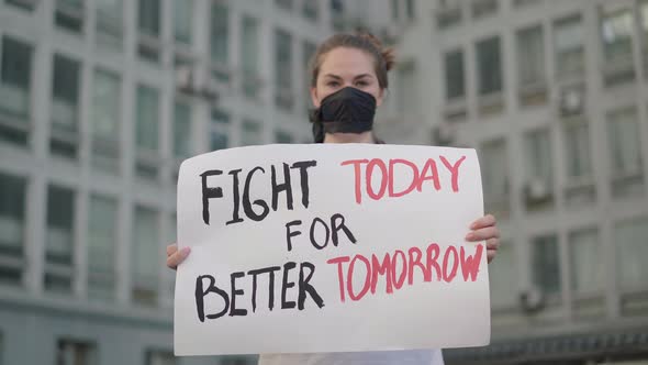 Rack Focus Changes From Serious Face of Activist To Banner with Slogan. Serious Beautiful Caucasian