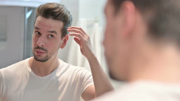 Young Man Fixing Hair in Mirror