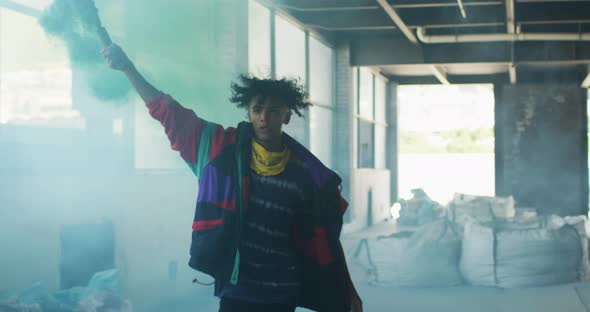 Mixed race man holding blue flare running through an empty building