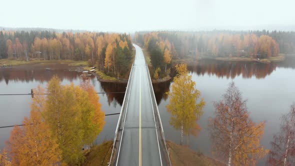 Aerial, decreasing, drone shot, above a bridge, surrounded by mist and autumn colors,, on a foggy, m