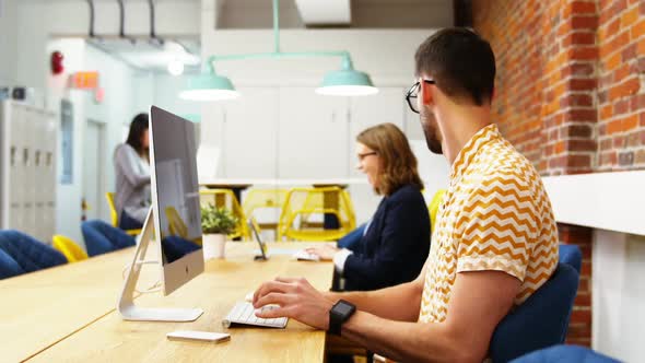 Group of executives discussing over computer at desk