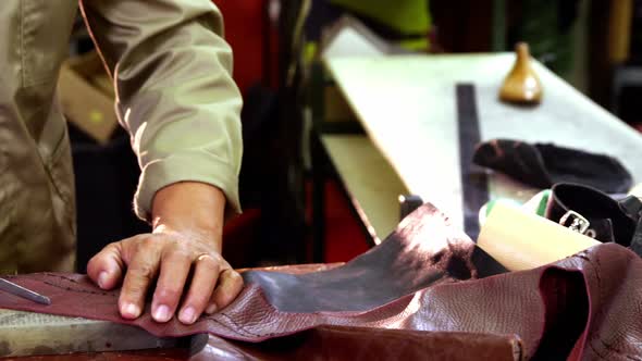 Cobbler cutting a piece of leather