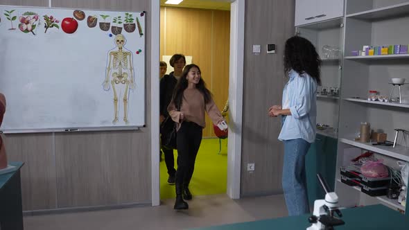 Female Teacher Greeting Pupils Entering Classroom