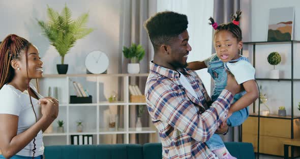 Young Father and Mother Playing with Daughter at Home