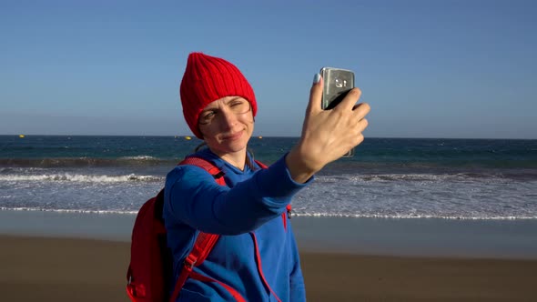 Active Hiker Woman Walks on the Beach and Makes Self Photo on Her Smartphone