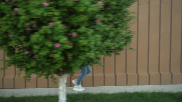 A Young Woman Runs Near a Shopping Center. The Girl Is Late and Running. Casual Wear.