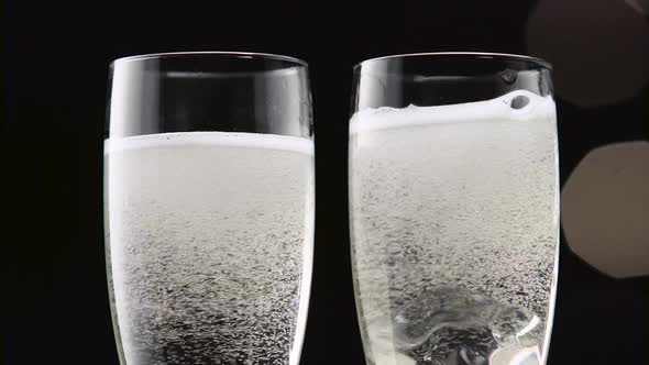 Two Flutes of Champagne with Ice on the Bottom. Bokeh Blinking Black Background. Close Up